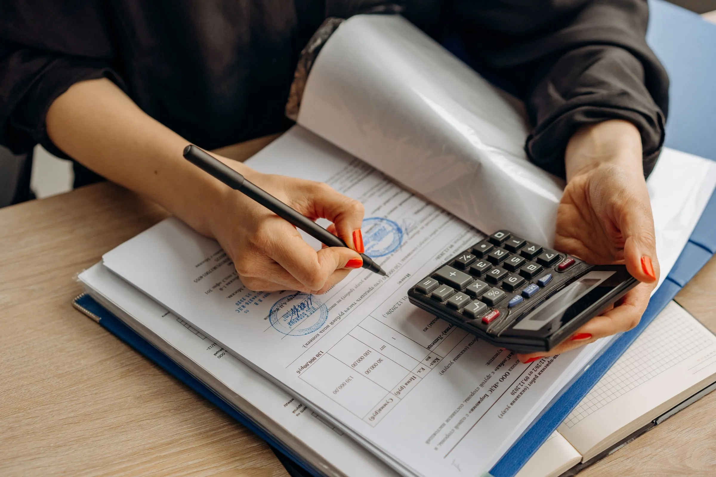 An accountant checking a document with a calculator in hand.